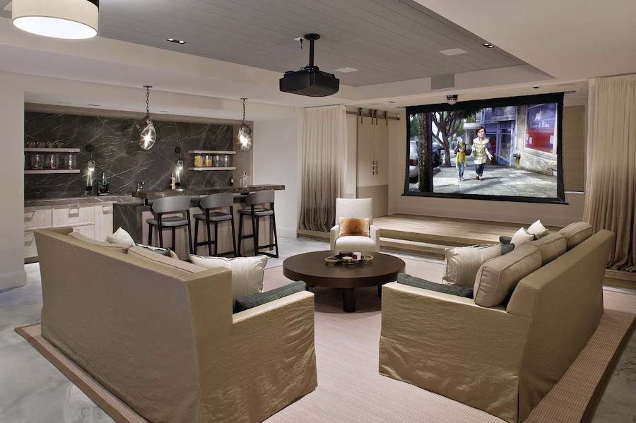 A Chicago media room with a drop-down screen, casual sofa seating, and a refreshment bar.
