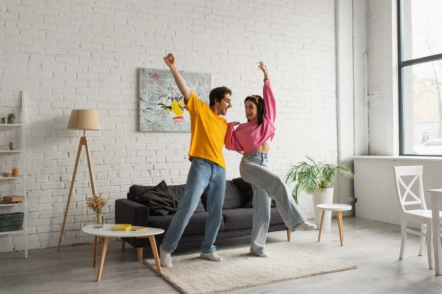 A couple dances happily in the middle of their living room.