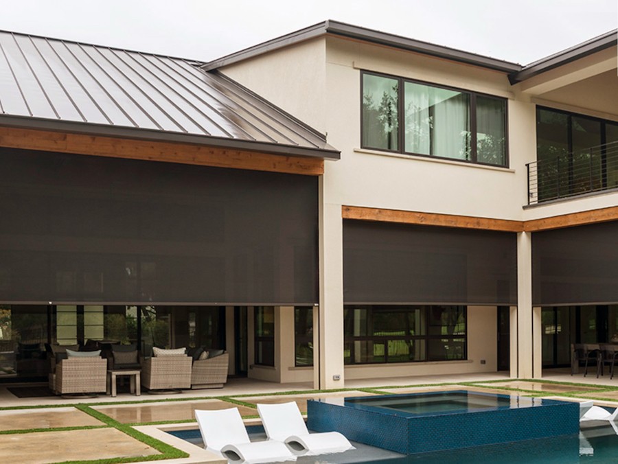 A view of a modern patio and pool area; the patios have partly lowered motorized outdoor shades.