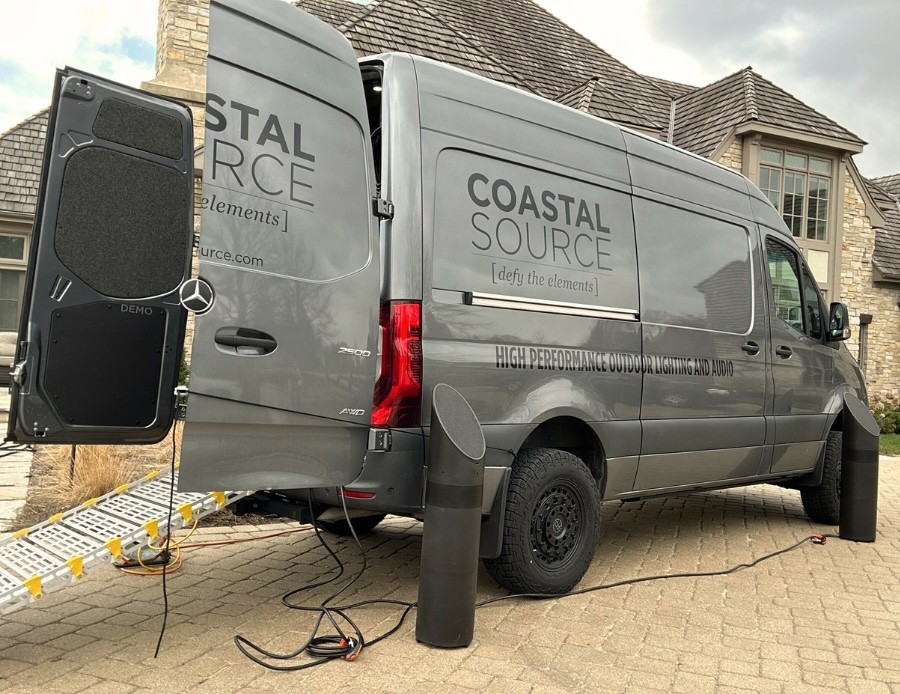 The Coastal Source demo van with open back doors sits in the driveway of a luxurious Midwest home.