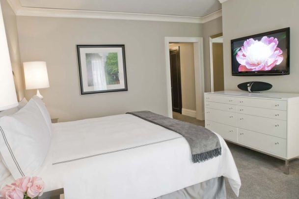 Bedroom with tv on wall and white comforter